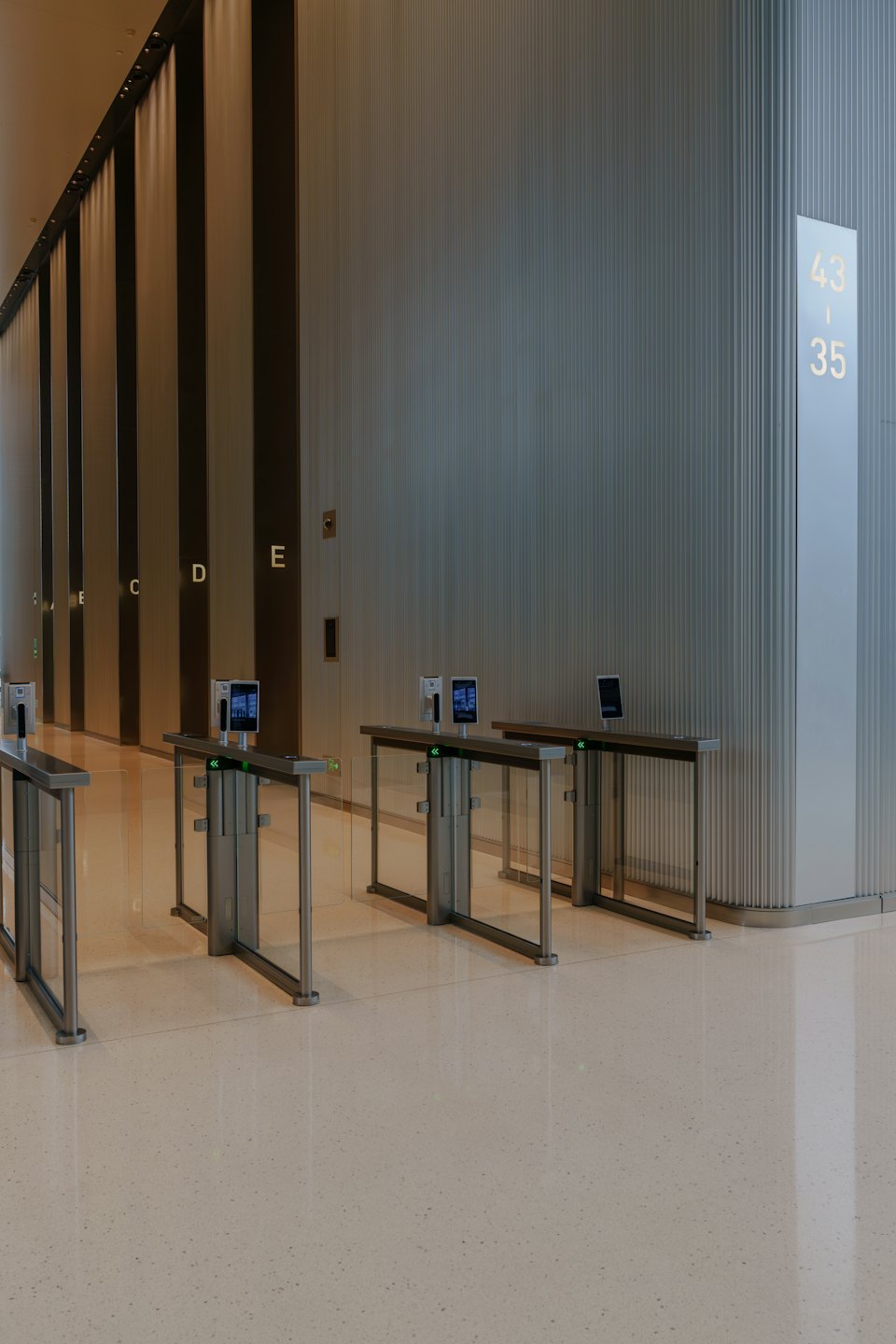 Glass security turnstiles stand in a modern office lobby.