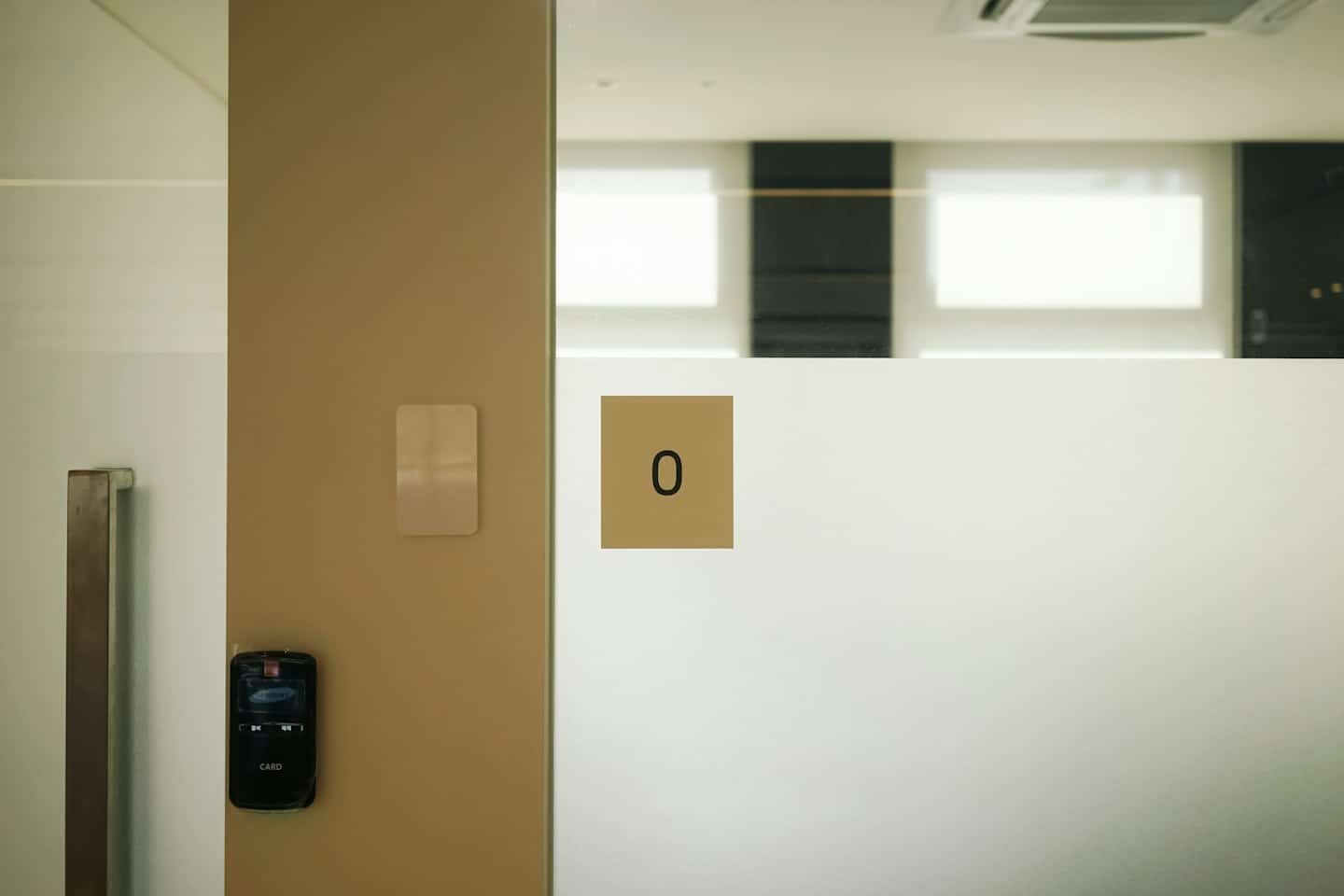 Black card reader mounted on a wall beside a glass door.