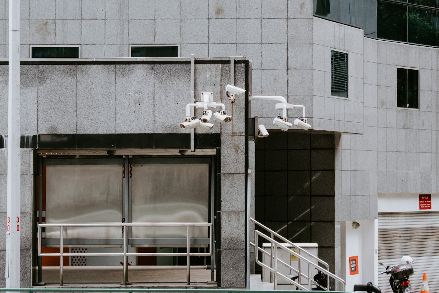 Modern office building entrance with security cameras and a scooter.