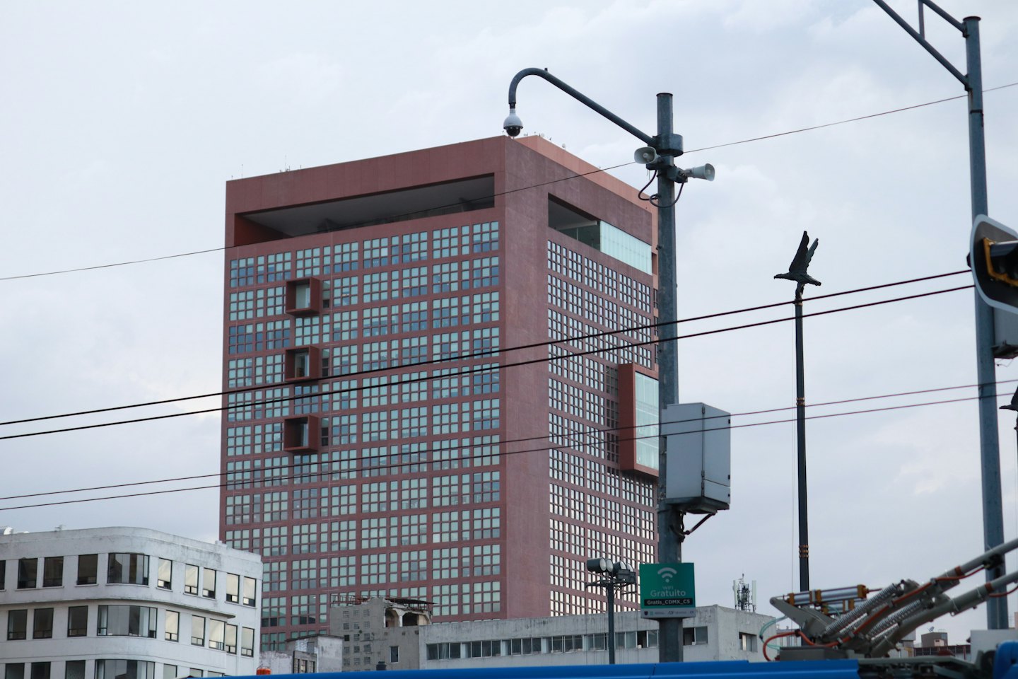 A tall brown building with grid windows stands behind urban utility poles.