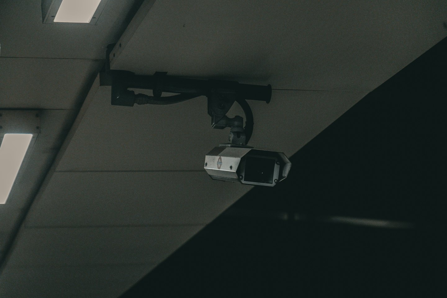 Security camera mounted on a textured grey ceiling.