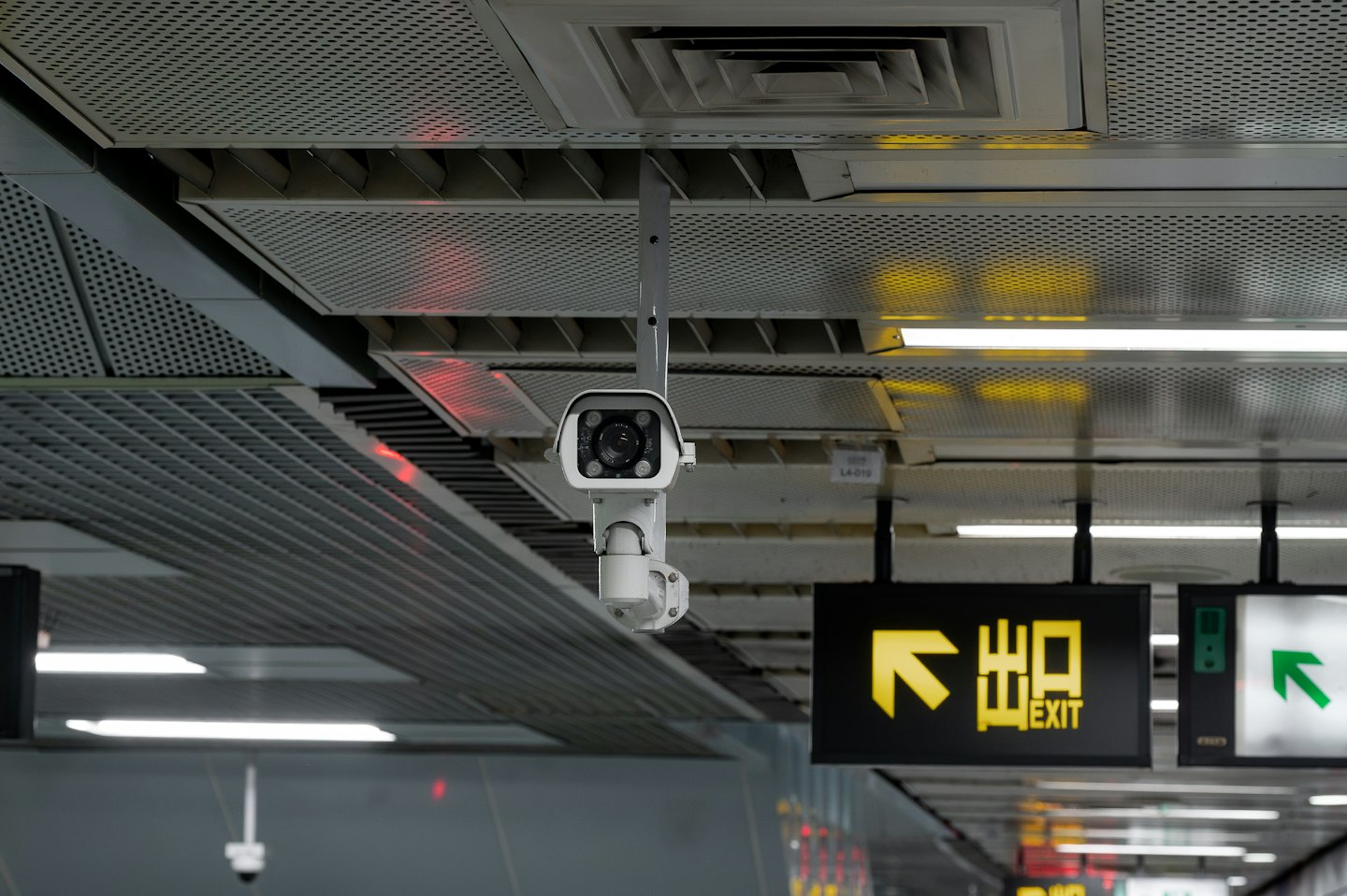 Security camera mounted on a ceiling above an indoor hallway.