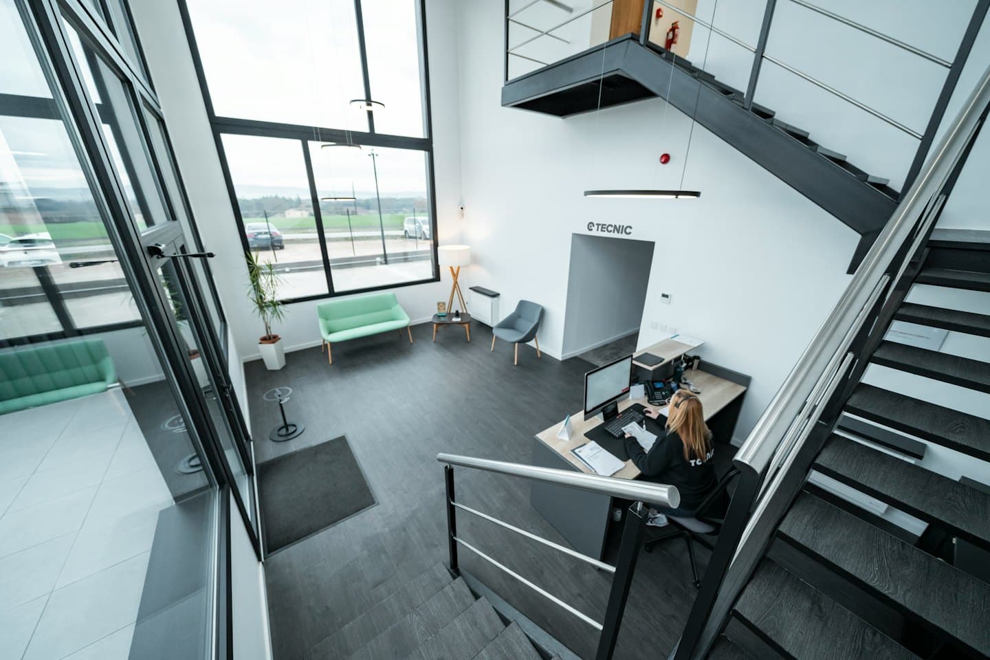 Receptionist working at a computer in a modern office lobby.