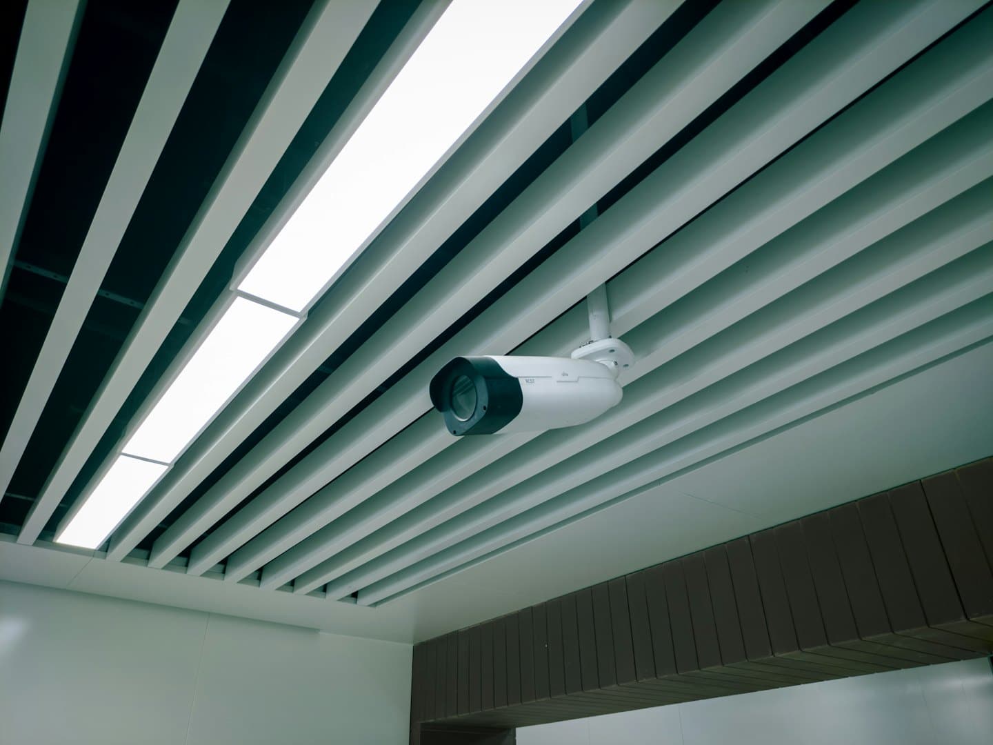 Security camera mounted on a modern slatted ceiling.