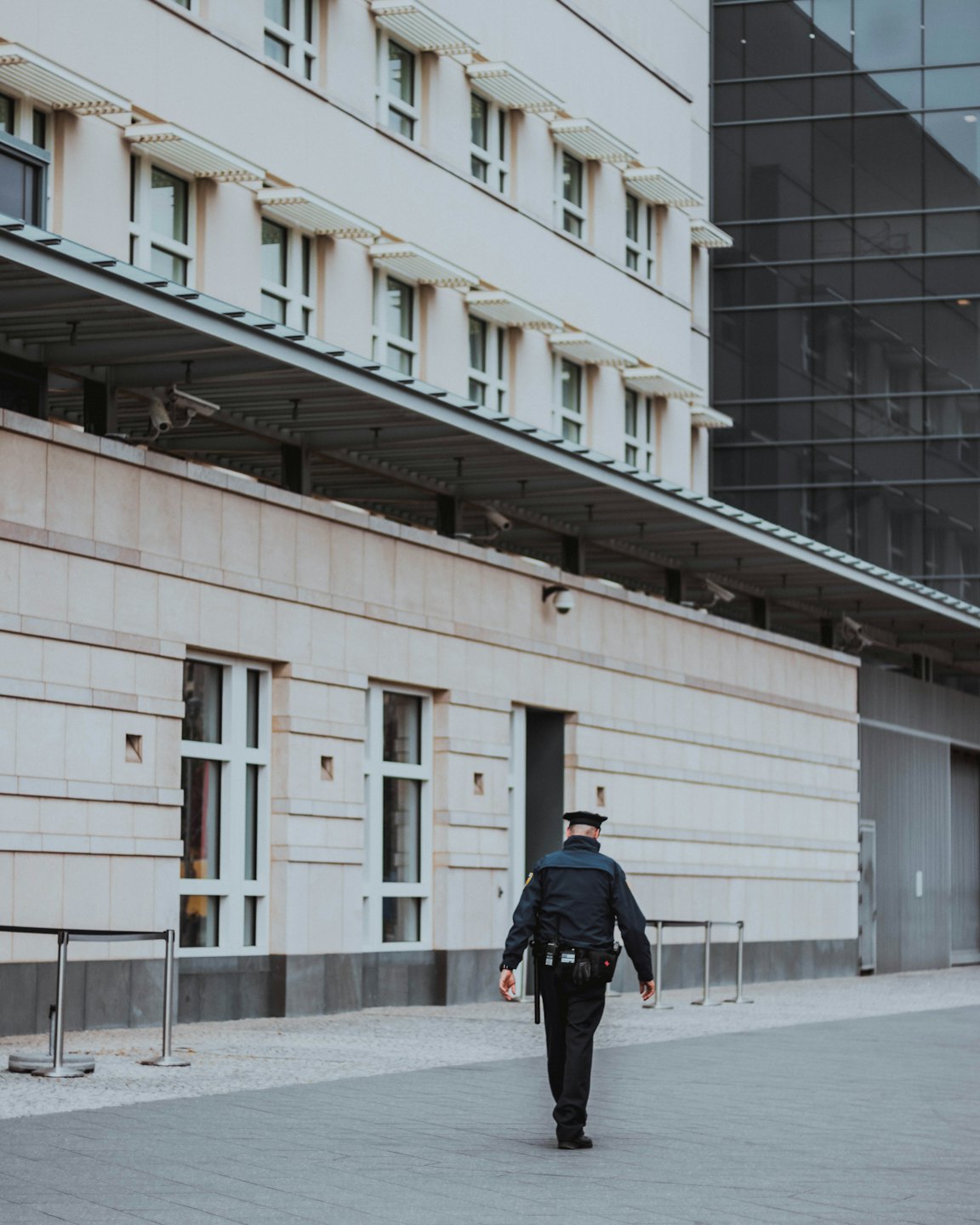 Security professional walks away from a modern building with cameras.